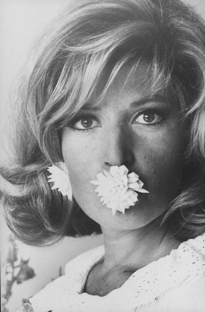 Actress Monica Vitti w. large flower earring in her mouth which is a bomb as she poses for her role as a spy in the movie thriller Modesty Blaze. (Photo by Stephan C. Archetti/Pix Inc./Time Life Pictures/Getty Images)