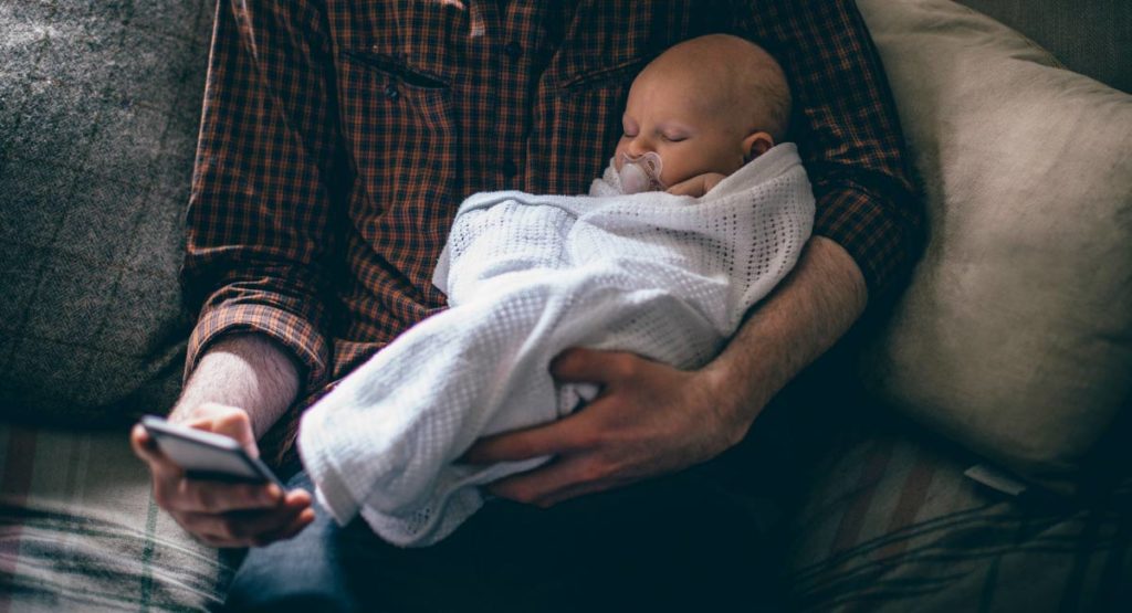 dad-holding-baby-and-checking-iphone